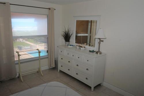 a bedroom with a dresser with a mirror and a window at WOW! Updated Oceanfront, Pool Front Spanish Main Condo 45! in Cocoa Beach