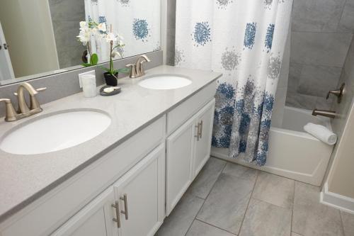 a bathroom with two sinks and a shower curtain at ChampionsGate- 1565 Four Bedroom Townhouse, Private Pool! in Davenport