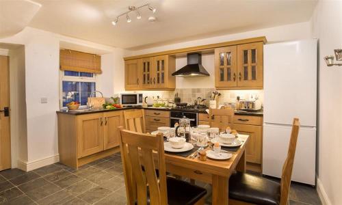 a kitchen with a wooden table with chairs and a kitchen with at The Cats Bield in Keswick