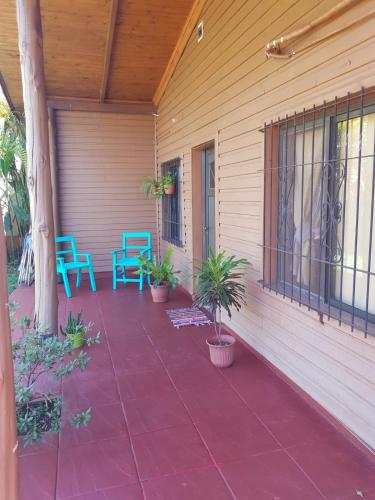 un porche con dos sillas azules y plantas. en Viví Iguazú Casa Familiar en Puerto Iguazú