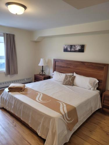 a bedroom with a large bed with a wooden headboard at Muskoka Lakes Hotel and Resorts in Port Carling