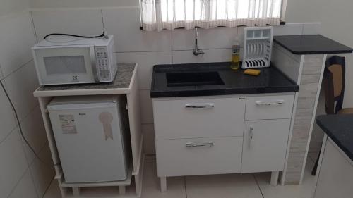 a small kitchen with a microwave and a stove at Hotel Pousada Riacho da Areia in Águas de Lindóia
