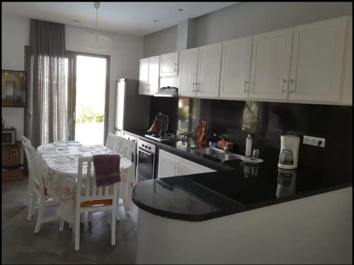 eine Küche mit weißen Schränken, einem Tisch und einer Arbeitsplatte in der Unterkunft Villa Toufitri in Agadir