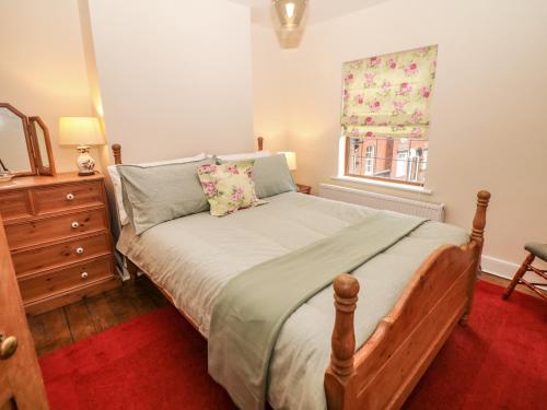 a bedroom with a bed with a dresser and a window at Mill Cottage in Leek