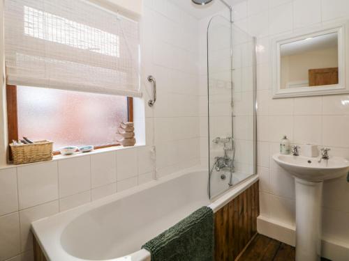 a bathroom with a bath tub and a sink at Mill Cottage in Leek