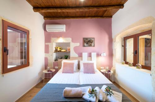 een slaapkamer met een wit bed en roze muren bij Cretan Lux Villa Heated Pool in Gavalochori