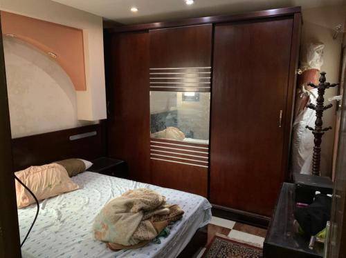 a bedroom with a bed and a large wooden cabinet at شقة مفروشة باامبابة in Cairo