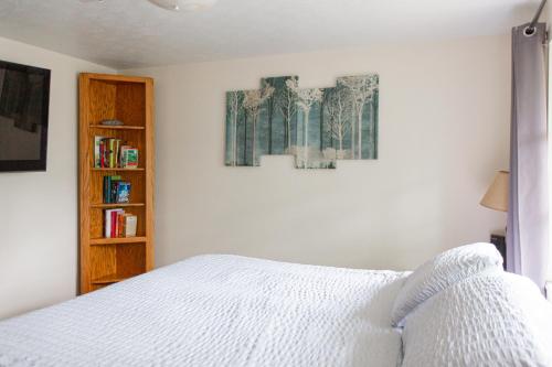 a bedroom with a white bed and a book shelf at Two Bedroom Home - Walking Distance from The Beach in Jacksonville Beach