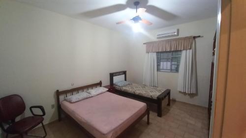 a bedroom with two beds and a chair and a window at Residência Manto Azul in Aparecida