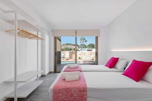 um quarto branco com uma cama grande e almofadas cor-de-rosa em VILLA NOKA em Cala en Blanes