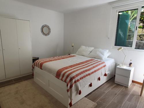 a white bedroom with a bed and a window at Casa das Feiteiras by AnaLodges in Ponta Delgada