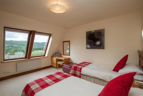 a bedroom with two beds and a desk and a window at Rothay 18 in Ambleside