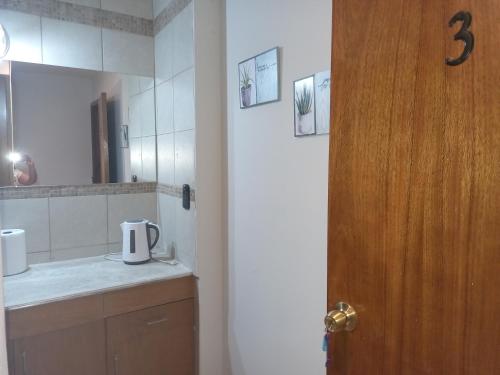 a bathroom with a sink and a mirror and a door at Nueva Era Apart in La Consulta