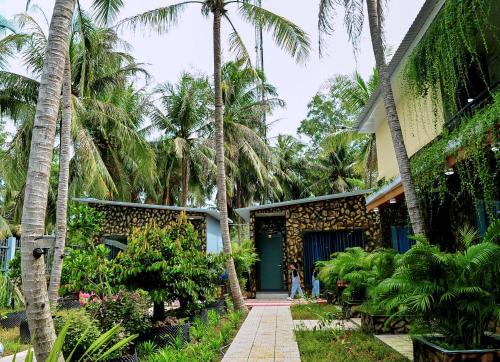 a house with a blue door and palm trees at Homestay Bảo Bình in Ben Tre