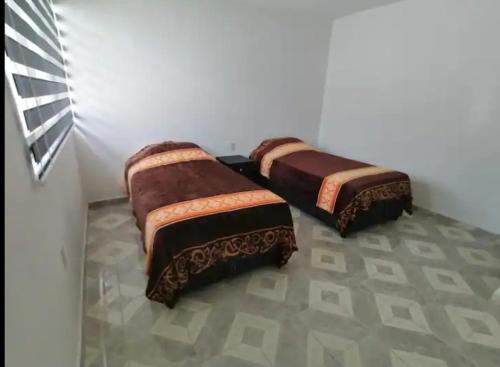 Hogar amplio y acogedor في إكسميكيلبان: سريرين يجلسون في غرفة بها جدار