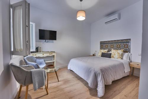 ein weißes Schlafzimmer mit einem Bett und einem Stuhl in der Unterkunft Casa Pureza in Sevilla