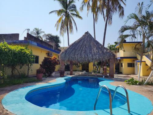una piscina frente a una casa con palmeras en CASA PLAYITA MELAQUE, en San Patricio Melaque