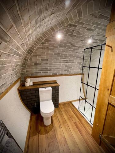 a bathroom with a toilet in a brick wall at Rabbits View in Rhayader