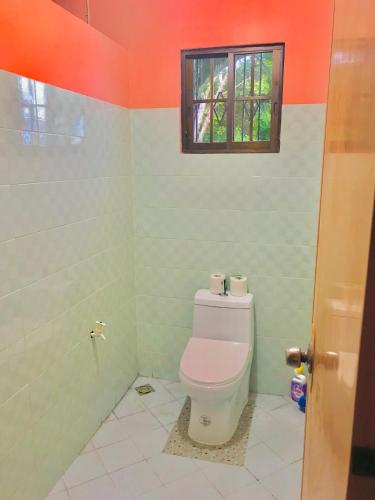 a bathroom with a toilet with a window above it at Sandra's holiday house in Oslob