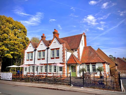 una casa blanca y roja al lado de la calle en The Bulls Head Inn en Ewhurst