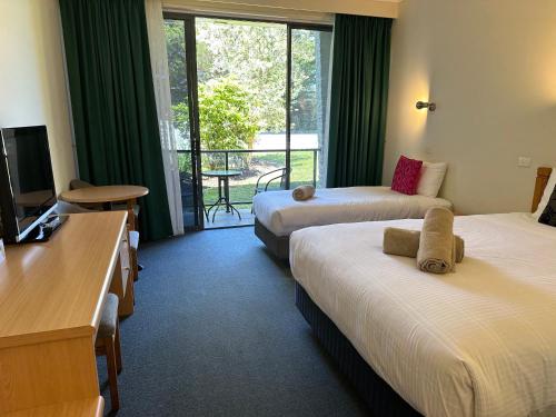 um quarto de hotel com duas camas e uma televisão em Banjo Paterson Motor Inn em Lakes Entrance
