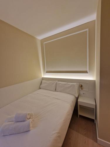 un pequeño dormitorio con una cama blanca con una luz encendida en Le Petit Palü- Barco, en Madrid