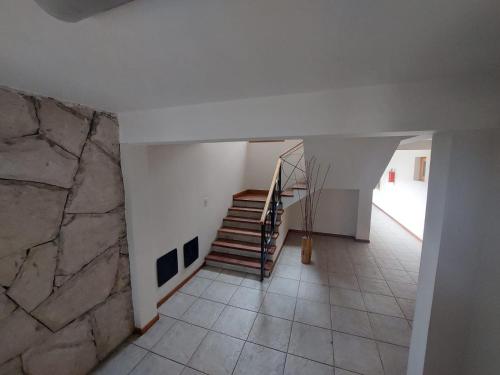 Habitación con escalera y pared de piedra. en Depto Ramayon - amancayalquileres en San Martín de los Andes