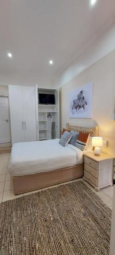 MaeStorm GardensAfrican apartement في شرق لندن: غرفة نوم كبيرة مع سرير كبير وطاولة