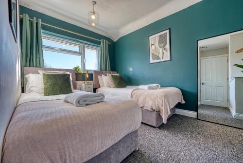 2 łóżka w pokoju z niebieskimi ścianami w obiekcie Stratton Heights by Apricity Property - 3 bedroom house, great for work or leisure, pet friendly w mieście Cirencester