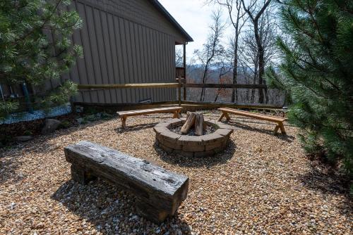 a backyard with two benches and a fire pit at stayNantahala - Smoky Mountain Cabins in Aquone