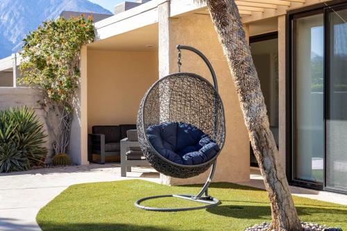 a wicker swing sitting on the front porch of a house at The Sunset House Pool & Spa in Palm Springs