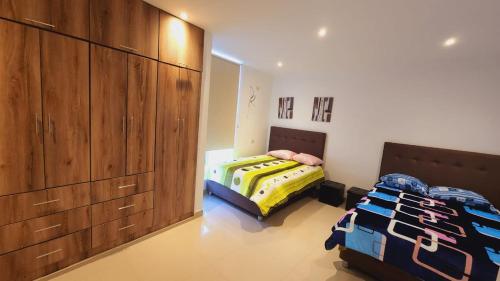 a bedroom with two beds and wooden cabinets at Departamento exclusivo en Ica in Ica