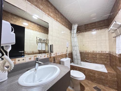a bathroom with a sink and a toilet and a tub at Royal Prestige Hotel in Dubai