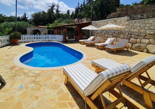 Gavalochori的住宿－Villa Nikolas，一个带躺椅和桌子的游泳池以及围栏