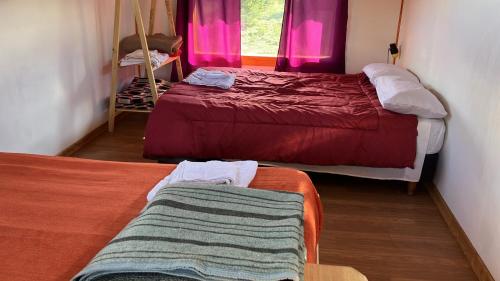 a room with two beds and a window with pink curtains at Casa de la ventana in Lago Meliquina