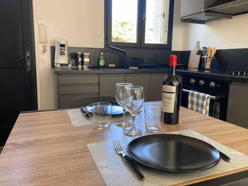 a table with a bottle of wine and glasses on it at Appartement duplex : Le Cosy in Montgeron