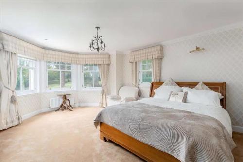 a bedroom with a large bed and windows at Superb 5 bedroom Villa 16 mins from City Centre in Musselburgh