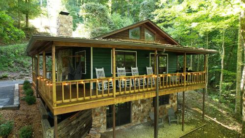a log cabin in the woods with a deck at stayNantahala - Smoky Mountain Cabins in Aquone