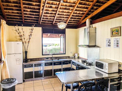 a kitchen with a refrigerator and a table with a microwave at MOOREA - The Golden Reef Bungalow Nuku Hiva in Temae