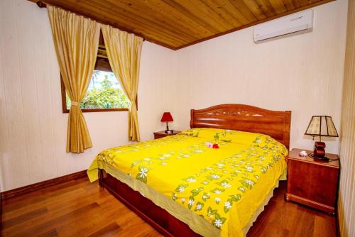 a yellow bed in a bedroom with a window at MOOREA - The Golden Reef Bungalow Nuku Hiva in Temae