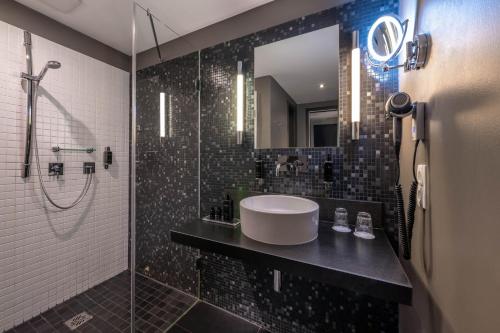 a bathroom with a sink and a shower with a mirror at Hotel du Nord, Hamburg-Volksdorf in Hamburg