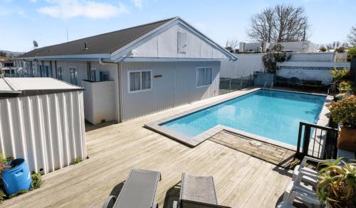 a large swimming pool on a wooden deck next to a house at Kowhai Motel Rotorua in Rotorua