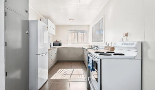 a white kitchen with a stove and a refrigerator at Kowhai Motel Rotorua in Rotorua
