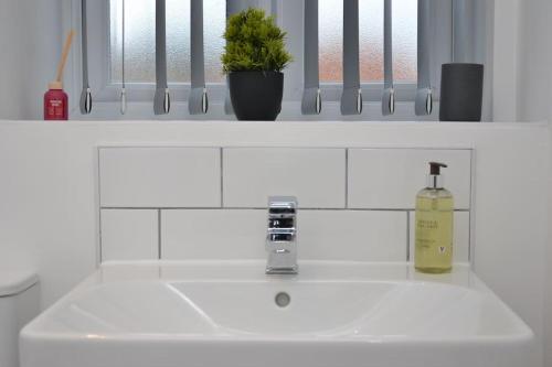 a bathroom sink with a bottle of soap on it at Erasmus House - 3 Bedrooms - City Centre, Netflix, WIFI, Free Private Parking in Derby