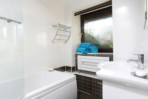 a white bathroom with a sink and a bath tub at Old Coach House in Ambleside