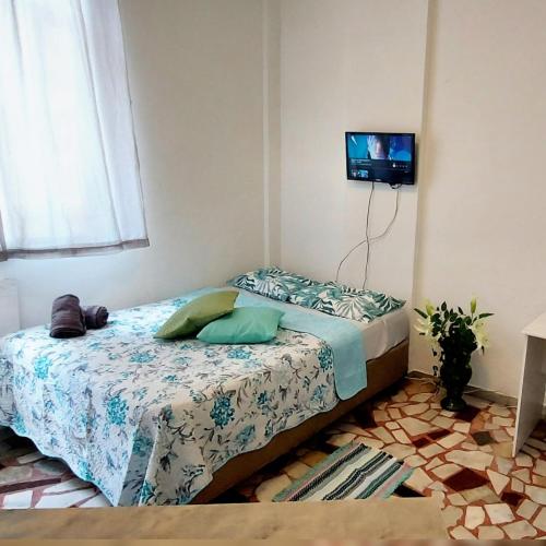 1 dormitorio con 1 cama y TV en la pared en Studio Verde-Coral Copacabana, en Río de Janeiro