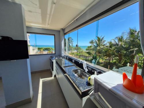 a kitchen with a large window with a view of the ocean at Apt FRENTE MAR MEAIPE COMPLETO in Guarapari