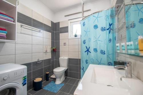 een badkamer met een toilet, een wastafel en een wasmachine bij Konstantinos holidays house in Laganas