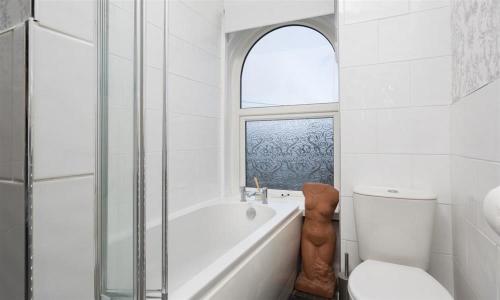 een badkamer met een bad, een toilet en een raam bij Biskey Steps in Bowness-on-Windermere