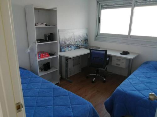 a bedroom with two beds and a desk and a window at Excelente apartamento en Montevideo in Montevideo